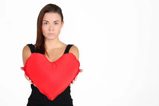 Beautiful young woman holding a red heart. White background 