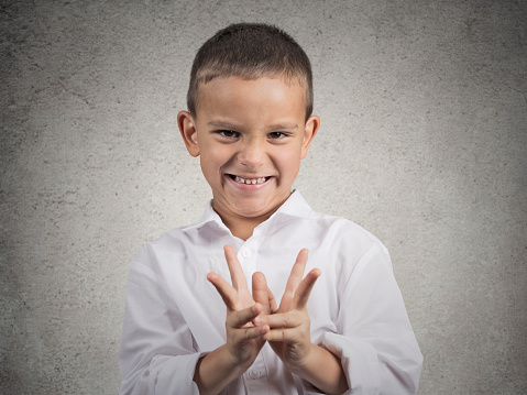 Closeup portrait sneaky sly scheming child boy plotting something bad, revenge isolated grey background. Negative human emotion facial expression feeling attitude body language. Children competition