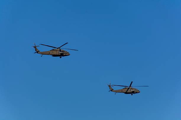 Two military helicopters flying against blue sky