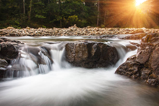 Landscape of mountain river in sunshine. View of the stony rapids. Fast jet of water at slow shutter speeds give a beautiful magic effect.