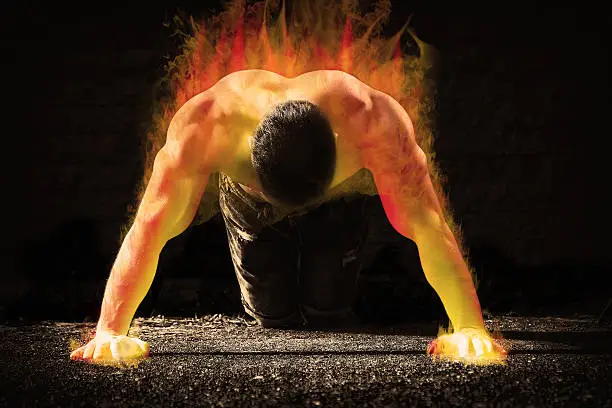 Photo of Young fit man in fire showing his muscles -- toned