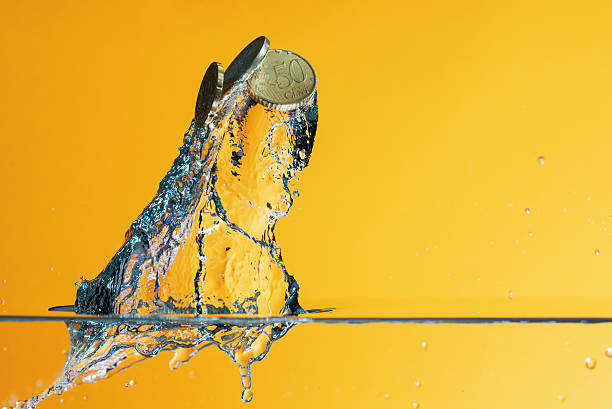 istock Euro coins in water splash over yellow background 598688144