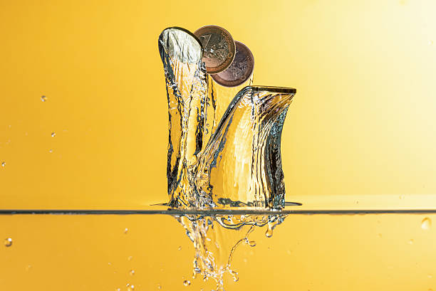 istock Euro coins with water splash over yellow background 598688246