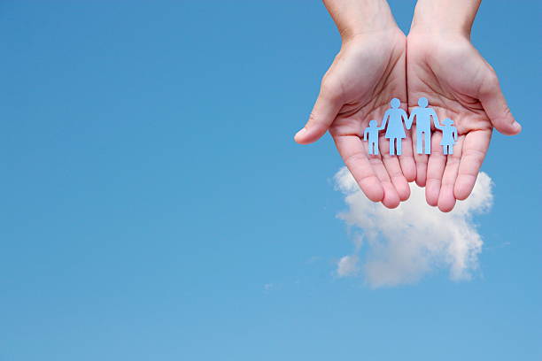 istock Paper family in hands on blue sky background welfare concept 598699406