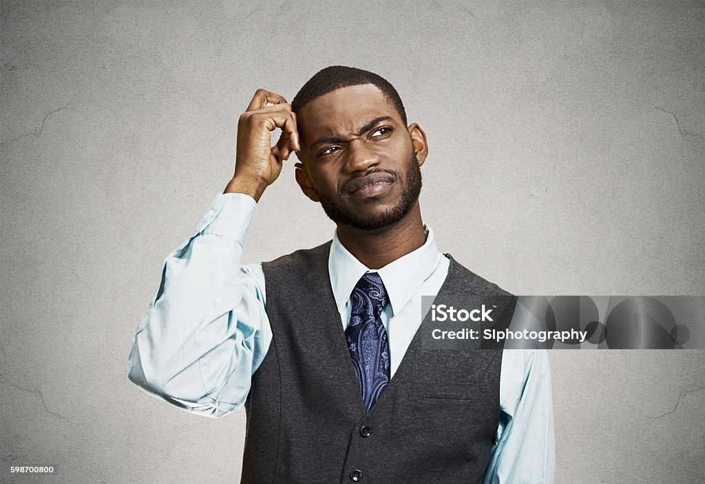 Confused business man, short term memory loss Closeup portrait young company business man thinking, daydreaming trying hard to remember something looking upward, isolated black background. Negative emotions, facial expressions, feelings, reaction Reminder Stock Photo