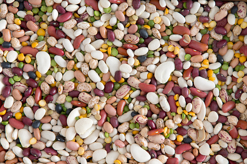 Full frame background of 15 assorted mixed beans and legumes including kidney, lima, black-eyed, yellow eye, garbanzo and pinto beans, lentils, split peas, overhead view in a layer