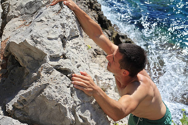 istock Attractive muscular Man climbing on mountain rocks against sea 598704906