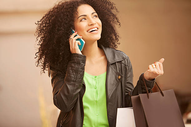 African american woman on the phone with shopping bags stock photo