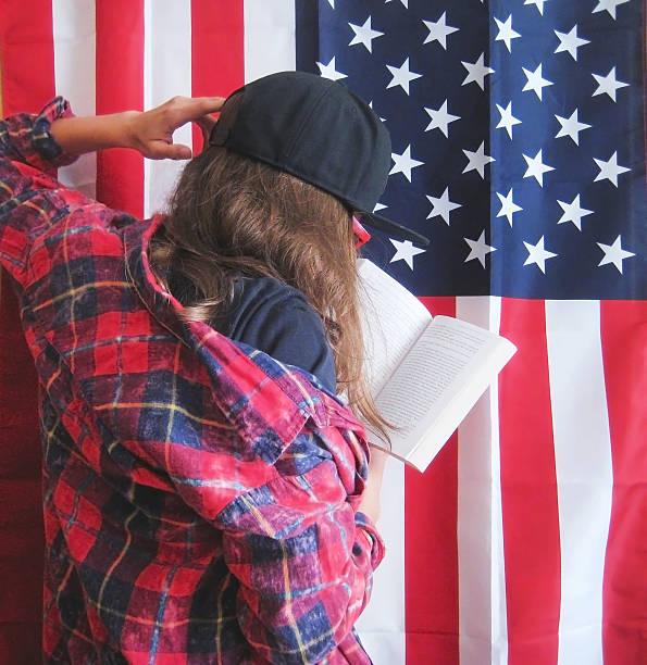 istock Girl reading a book against american flag background 598709780