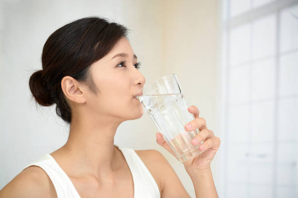 女性水を飲む - glass cup ストックフォトと画像