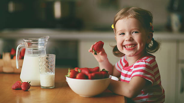 istock happy child girl eats strawberries in summer home kitchen 598711674