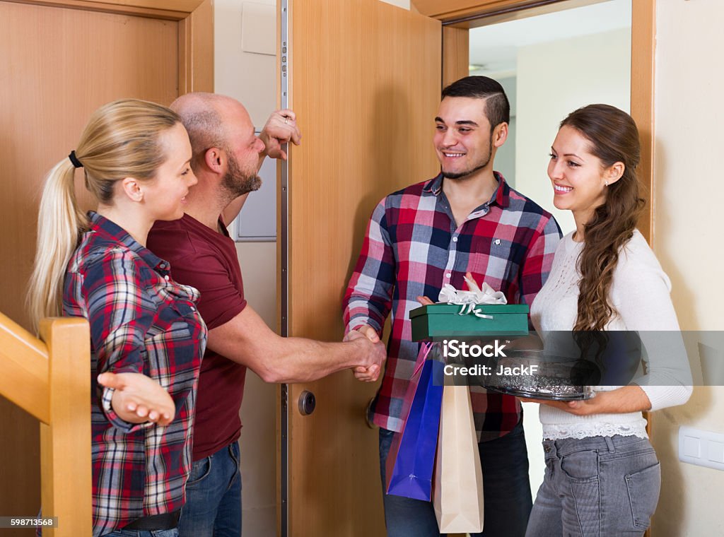 Warm welcome of joyful friends Warm welcome of joyful friends holding gifts and sweets Greeting Stock Photo