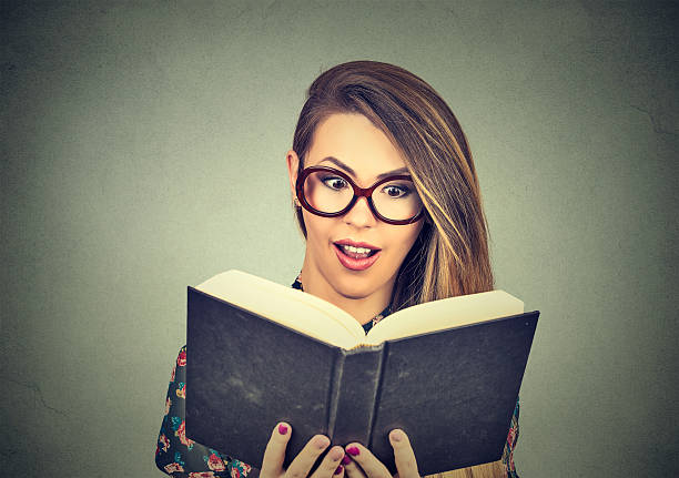 istock young woman in glasses reading big book 598714516