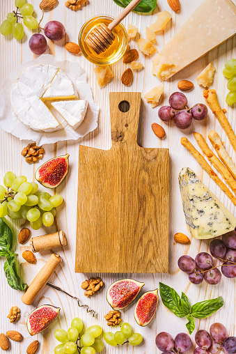 Cheese platter with fruits and honey on the rough wooden background. Vertical shoot from above.