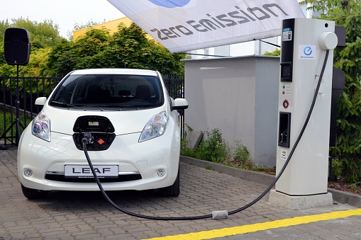 Warsaw, Poland - July 25th, 2013: Zero emission Nissan Leaf parked on the electric charging point. The Leaf model is the most popular electric compact car in Europe.