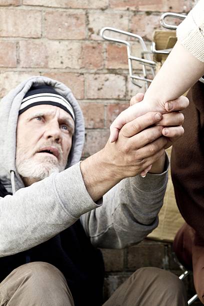 Homeless man receiving a helping hand from a passer by
