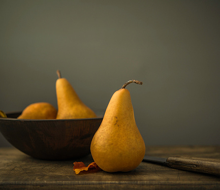 Organic pears in wooden bowl with knife and chopping board