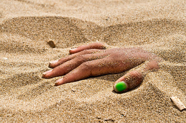 on the beach hand in rigor mortis protruding from the sand
