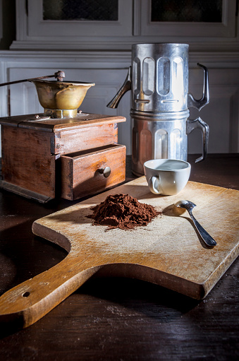 still life with a coffee mill a  a neapolitan coffee  moka and  a white cup and steel little spoon beside a pile of coffe powder