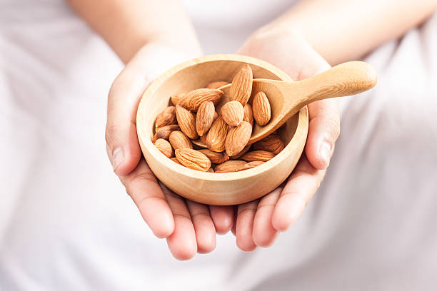istock almonds in a wooden spoon and bowl on hand 598802230