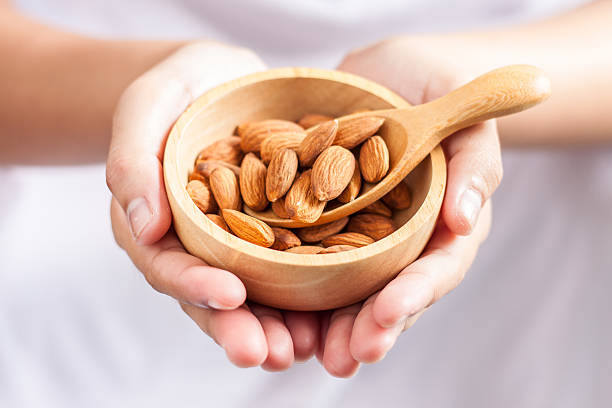 istock almonds in a wooden spoon and bowl on hand 598802342