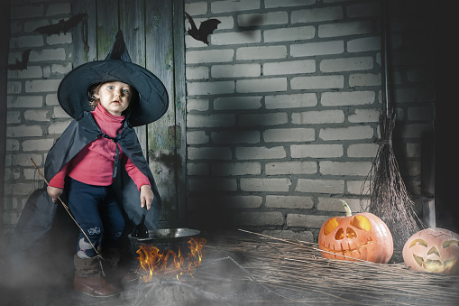 Little witch making a magic potion at Halloween night. Horror.