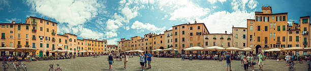 Lucca, Italy - August 17, 2016: 360 degree panorama of the Piazza Anfiteatro in the middle of lucca, Tuscany, Italy. Tourists walk over the place or sitting at one of the many cafes. 