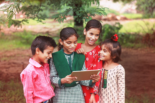Rural group of children enjoying digital tablet outdoor nature.       