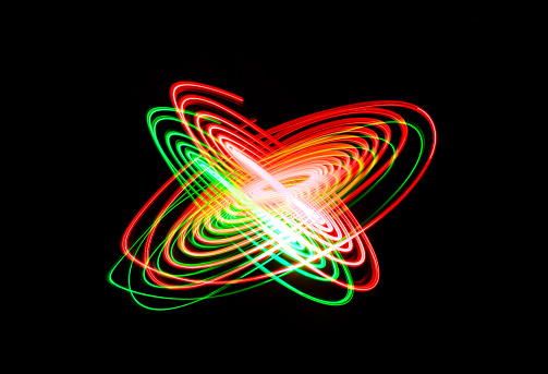 LED light painting against black background creating colorful intertwined spirals of green and red