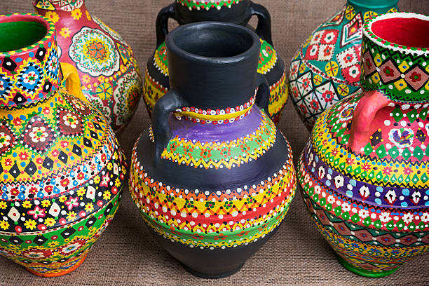 Still life of three artistic painted colorful handcrafted pottery vases on on sackcloth background