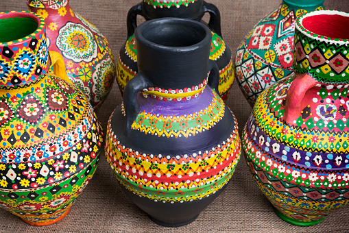 Still life of three artistic painted colorful handcrafted pottery vases on on sackcloth background