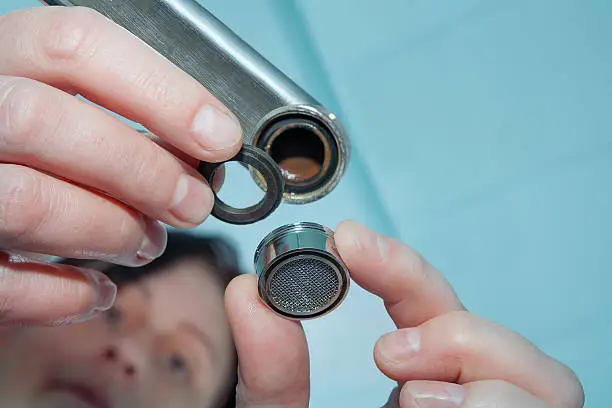 Photo of Women handyman replace tap aerator, plumber hand close-up.