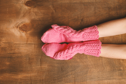 Hands girl dressed in pink mittens under wooden background. Copy space. Disclosed palms