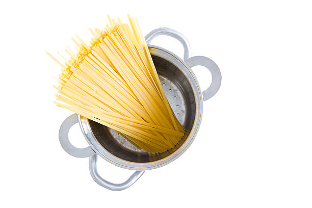 Overhead view of a bundle of dried fettuccine pasta standing upright in a pot ready for boiling for an Italian pasta recipe, isolated on white