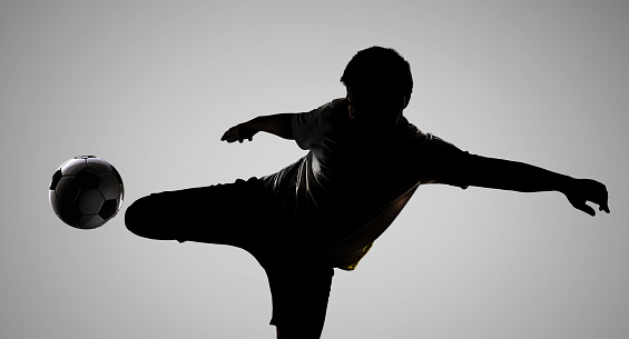 silhouette football player kicking the ball with stadium background