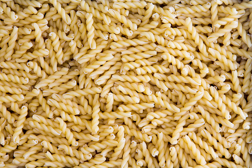 Background texture of dried organic gemelli pasta meaning twins, formed of twisted strands of pasta in a spiral form for use in traditional Italian and Mediterranean cooking