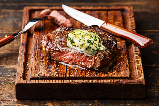 Grilled Medium rare steak Ribeye with herb butter on cutting board
