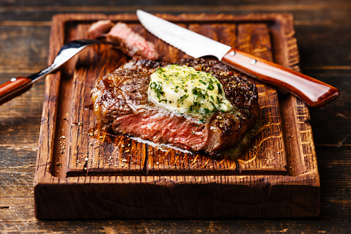 Grilled Medium rare steak Ribeye with herb butter on cutting board
