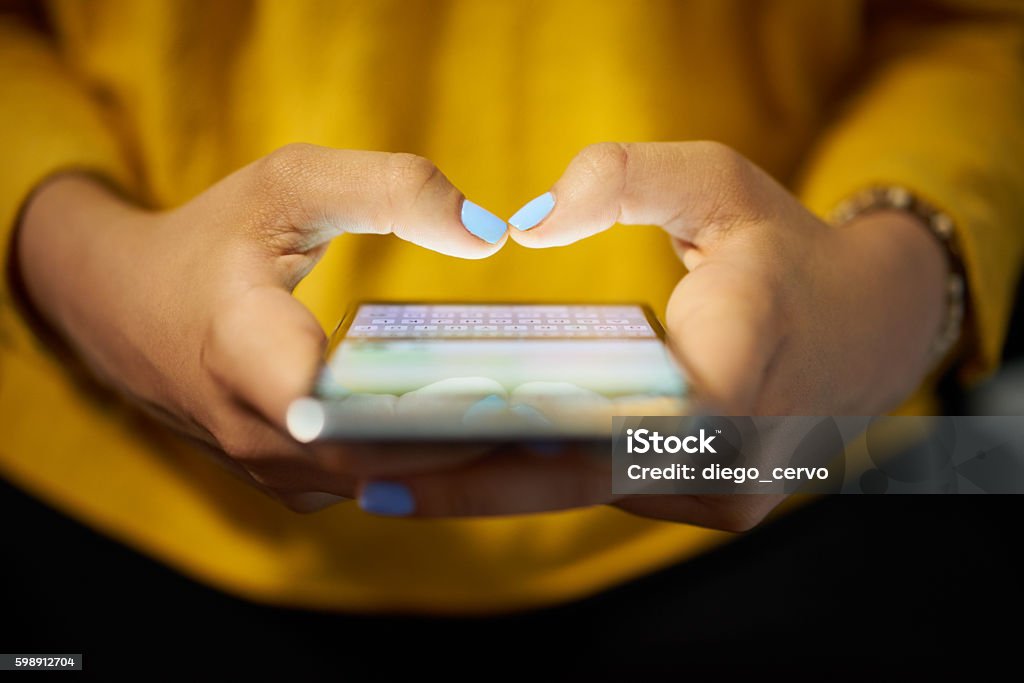 Mujer escribiendo mensaje telefónico en la red social por la noche - Foto de stock de Teléfono móvil libre de derechos