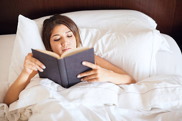 istock Woman reading a book in her bed 598918364