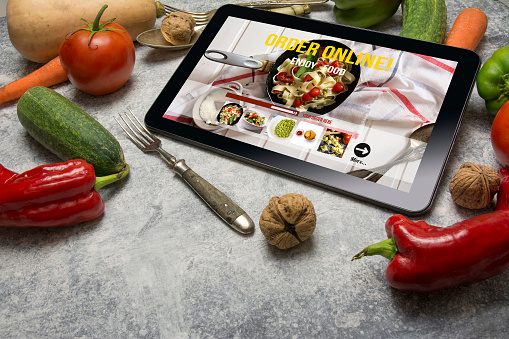 Tablet with Online food Delivery app on screen. Healthy food concept