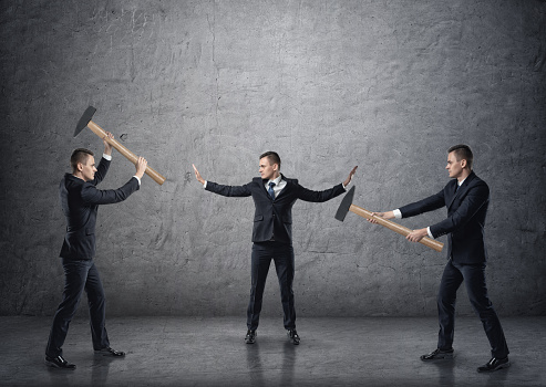 Businessman with raised hands separating two fighting businessmen with hammers. Conflicts and disputes. Collision and controversy. Pulling apart.