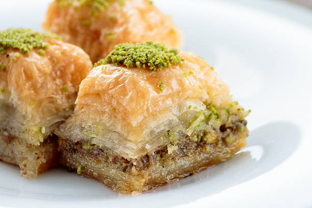 baklava con pistachos y nueces sobre plato blanco - baklawa fotografías e imágenes de stock