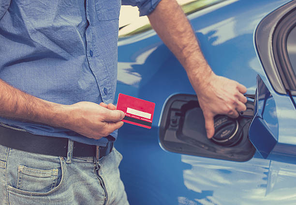 man with credit card opening fuel tank of new car - currency odometer car gasoline imagens e fotografias de stock