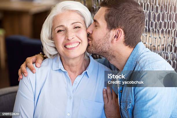 Positive Man Kissing His Grandmother Stock Photo - Download Image Now - Grandmother, Grandson, Adult