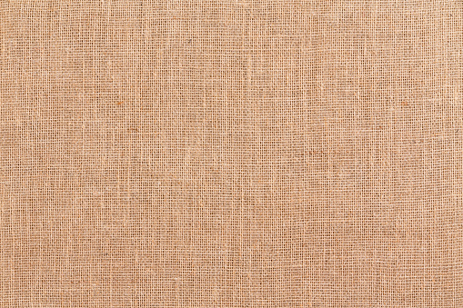 Full frame brown woven burlap or hessian textile background texture made from woven natural fibres viewed close up overhead