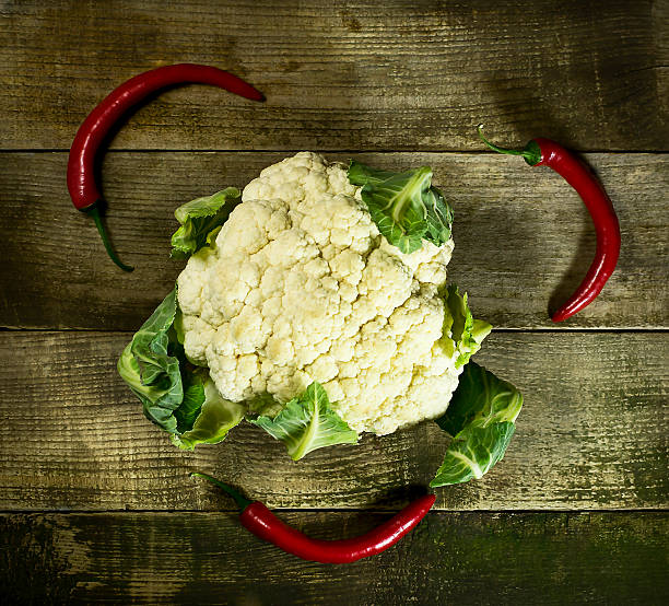 istock Fresh Cauliflower with red hot peppers on wooden background 598934150