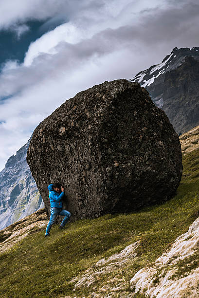 Sisyphus puhing a boulder up the hill Photo of a man pushing a boulder up the hill, a metaphor for Sisyphus sisyphus stock pictures, royalty-free photos & images