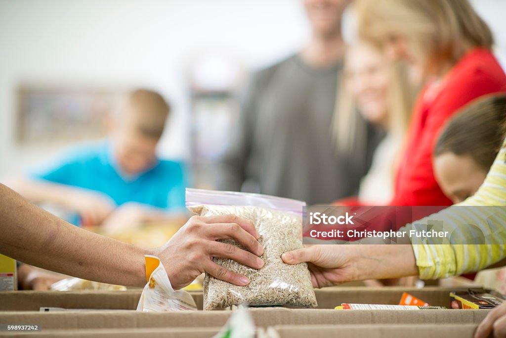 Sorting Non Perishable Foods A group of volunteers are working at a food bank and are sorting non perishable food items into boxes. Food Stock Photo