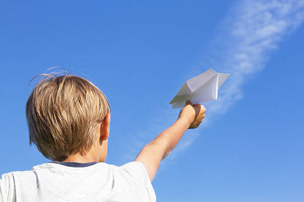 istock Boy with paper plane against blue sky. Low angle view 598937498